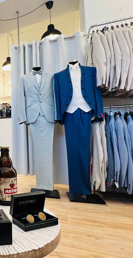 Anzüge auf Kleiderstangen und zwei Hochzeitsanzüge an Puppen im Gentlemen’s Club des Hochzeitshaus Schubert