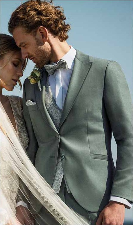 Bräutigam im grünen Hochzeitsanzug mit Weste neben der Braut